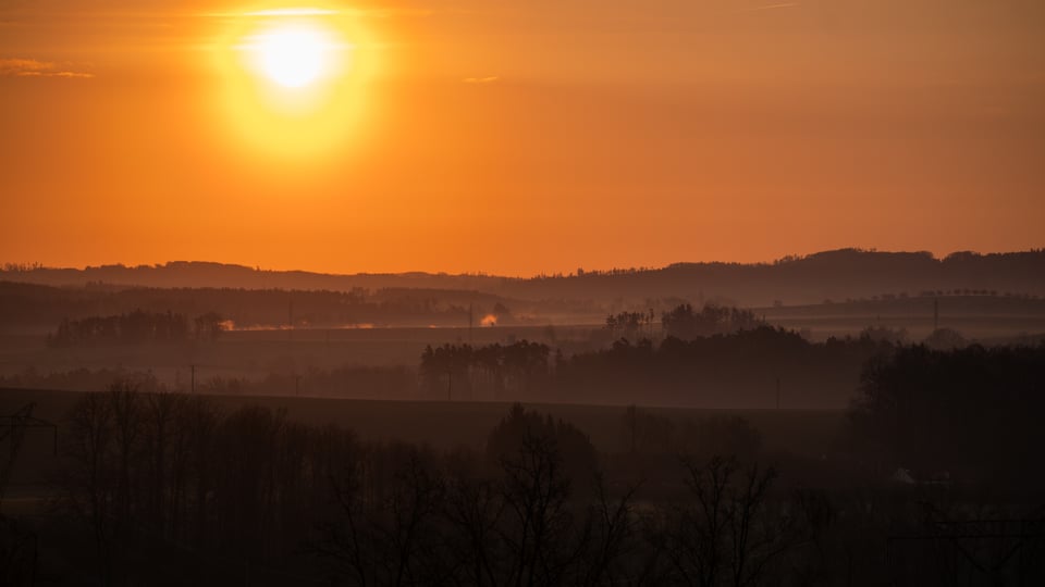 Východ slunce nad zvlněnou krajinou
